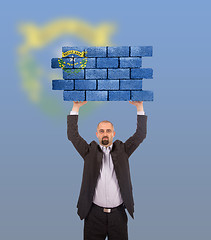 Image showing Businessman holding a large piece of a brick wall