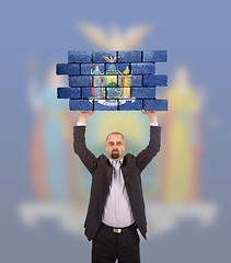 Image showing Businessman holding a large piece of a brick wall