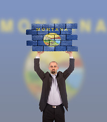 Image showing Businessman holding a large piece of a brick wall