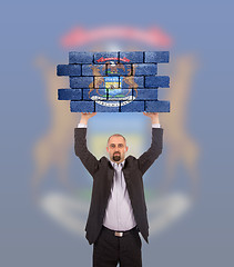 Image showing Businessman holding a large piece of a brick wall