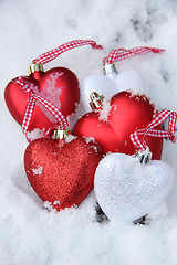 Image showing Red and white heart ornaments in snow