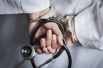 Image showing Female Doctor or Nurse In Handcuffs Holding Stethoscope