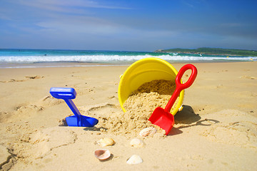 Image showing Child's beach bucket and spade on a sandy beach with seashells