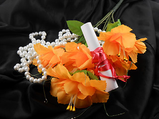 Image showing orange flowers, white paper and white diamonds on black background