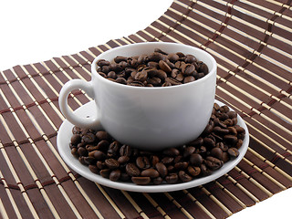 Image showing Coffee beans with coffee on bamboo background