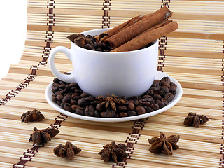 Image showing white cup with coffee and cinnamon near star anise over bamboo table