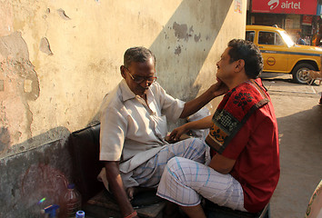 Image showing Street barber shaving a man on a street in Kolkata