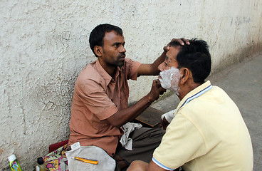Image showing Street barber shaving a man on a street in Kolkata