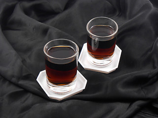 Image showing two glasses with red wine on black material background