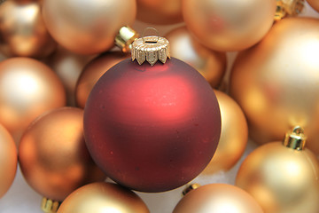 Image showing Red ornament on a pile of golden ornaments