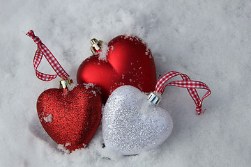 Image showing Red and white heart ornaments in snow