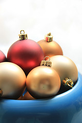 Image showing red and golden christmas ornaments in a blue bowl
