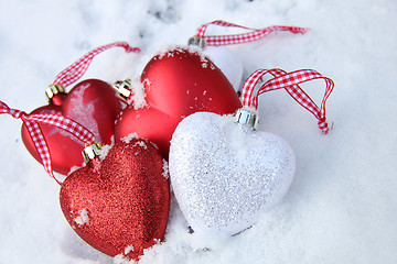 Image showing Red and white heart ornaments in snow