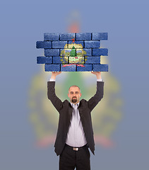 Image showing Businessman holding a large piece of a brick wall