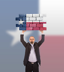 Image showing Businessman holding a large piece of a brick wall