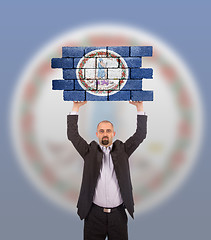 Image showing Businessman holding a large piece of a brick wall