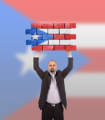 Image showing Businessman holding a large piece of a brick wall