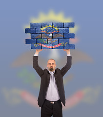 Image showing Businessman holding a large piece of a brick wall