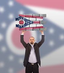 Image showing Businessman holding a large piece of a brick wall