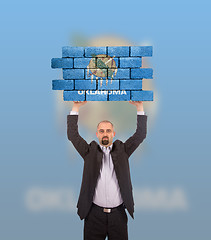 Image showing Businessman holding a large piece of a brick wall