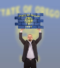 Image showing Businessman holding a large piece of a brick wall