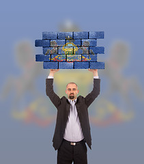 Image showing Businessman holding a large piece of a brick wall