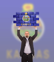 Image showing Businessman holding a large piece of a brick wall