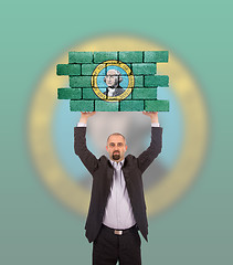 Image showing Businessman holding a large piece of a brick wall