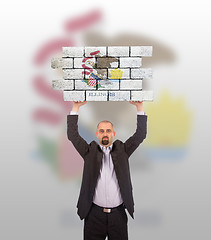 Image showing Businessman holding a large piece of a brick wall