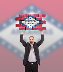 Image showing Businessman holding a large piece of a brick wall