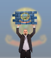 Image showing Businessman holding a large piece of a brick wall