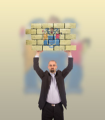 Image showing Businessman holding a large piece of a brick wall