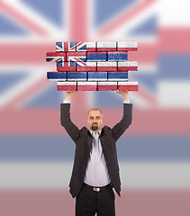 Image showing Businessman holding a large piece of a brick wall