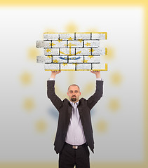 Image showing Businessman holding a large piece of a brick wall