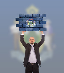 Image showing Businessman holding a large piece of a brick wall