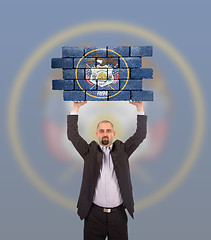 Image showing Businessman holding a large piece of a brick wall