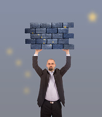 Image showing Businessman holding a large piece of a brick wall