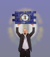 Image showing Businessman holding a large piece of a brick wall