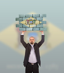 Image showing Businessman holding a large piece of a brick wall