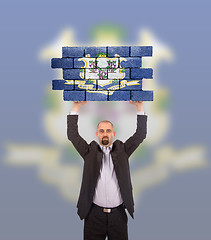 Image showing Businessman holding a large piece of a brick wall