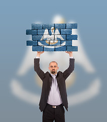 Image showing Businessman holding a large piece of a brick wall