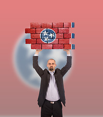 Image showing Businessman holding a large piece of a brick wall