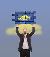 Image showing Businessman holding a large piece of a brick wall