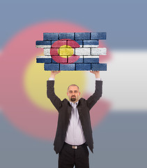 Image showing Businessman holding a large piece of a brick wall