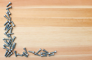 Image showing Socket head screws as L-shape border on woodgrain background