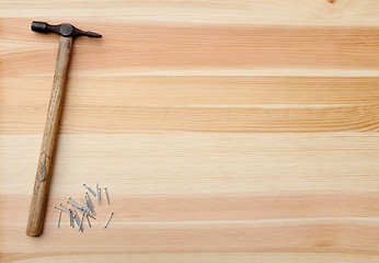 Image showing Hammer and metal panel pins on a woodgrain background