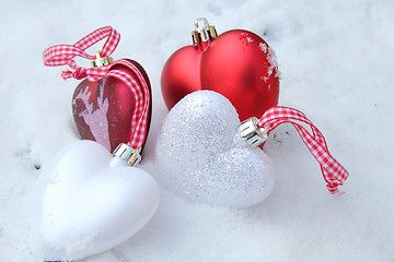 Image showing Red and white heart ornaments in snow