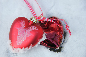 Image showing Red and white heart ornaments in snow