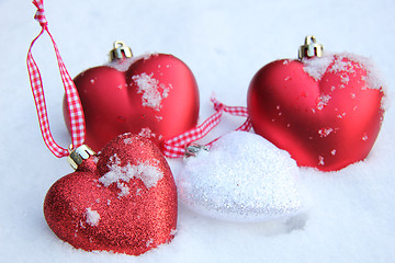 Image showing Red and white heart ornaments in snow