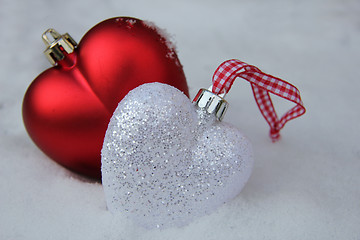 Image showing Red and white heart ornaments in snow